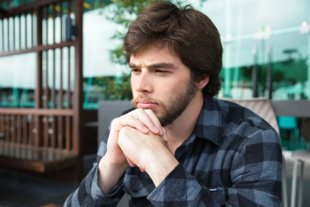 A realistic young adult man looking concerned and slightly worried
